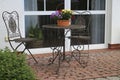 Metal table decorated with a flower basket and chairs on a small patio Royalty Free Stock Photo