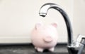 Metal tap and blurred piggy bank. Water saving concept Royalty Free Stock Photo