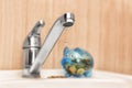 Metal tap and piggy bank on sink. Water saving concept Royalty Free Stock Photo