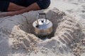 Metal teapot on camping kettle fire burner in a hole dug in the sand on a beach. Travel camping outdoor portable hot water