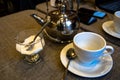 A metal teapot for tea brewing, a white ceramic cup, a glass vase for sugar on a table in a cafe. Royalty Free Stock Photo