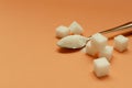 Metal teaspoon full of sugar and sugar cubes on the orange background.Empty space