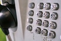 Metal telephone dial in the public phone booth with black letters and numbers on the silver plated buttons