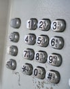 Metal telephone dial in the public phone booth with black letters and numbers on the silver plated buttons Royalty Free Stock Photo