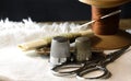 METAL THIMBLES WITH COTTON THREAD ON AN OLD WOODEN SPOOL, DARNING NEEDLE, DARNING YARN AND A PAIR OF SCISSORS