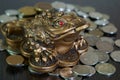 A metal toad next to a stack of coins. Royalty Free Stock Photo