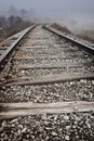 Train tracks leading around a curve and off into the fog Royalty Free Stock Photo