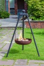 Metal tripod fireplace on grass with burning firewood