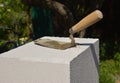 Metal trowel with wooden handle on the aerated concrete block