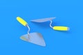 Metal trowels with yellow handle on blue background