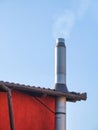 Metal tube pipe chimney on a house against blue sky