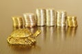 A metal turtle next to a stack of coins. Symbol of financial well-being