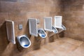 Metal urinals and one for children with an automatic sensor for flushing water after urinating. Men`s toilet in brown marble Royalty Free Stock Photo