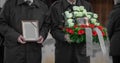 Metal urn or funeral container with ash of a deceased person at a memorial service. Undertakers seen carrying the picture and an Royalty Free Stock Photo