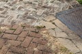 Metal utility cover and multiple brick herringbone patterns with patches of new concrete form a creative copy space background,