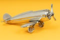 Metal vintage aircraft toy, with front propeller. Retro toy on yellow background Royalty Free Stock Photo