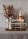 Metal vintage basket with books, dried flowers, ceramic Christmas decorations and lighted candles on the table in the interior Royalty Free Stock Photo