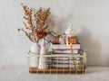 Metal vintage basket with books, dried flowers, ceramic Christmas decorations and lighted candles on the table in the interior Royalty Free Stock Photo
