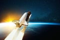 Metal vintage rocket with fire takes off into open starry space near the planet earth with sunset. Retro spacecraft lift off and Royalty Free Stock Photo