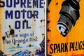 Metal vintage sign displaying a spark plug on an orange background and written content on the side