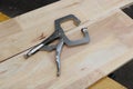 Vise grip locking clamp on wooden background