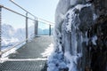 Metal walkway in snowy Murren, Switzerland, with chain link fence, icicles, mountains, and blue sky Royalty Free Stock Photo