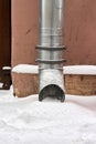 Metal water pipe on the corner of the house is filled with snow Royalty Free Stock Photo