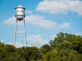 Metal water tank of small texas town Gruene standing high above trees on sunny day