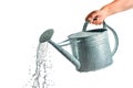 A metal watering can in hand isolated on a white or transparent background. Water splashes and droplets pour out of the Royalty Free Stock Photo