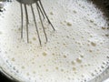 A metal whisk in a bowl with liquid dough