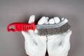 Metal wire brush with red plastic handle in a man's hand. White work leather gloves Royalty Free Stock Photo