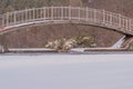 Metal and wood foot bridge over a frozen pond