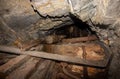 Metal and wooden timbering in abandoned old coal mine interior. Dangerous tunnels full of dirt and rusty equipment. Royalty Free Stock Photo