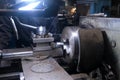 Metal worker operating working on lathe machine in workshop on factory.
