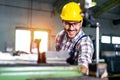 Metal worker turner operating lathe machine at industrial manufacturing factory.