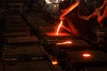 The metal workers is pouring molten metal to molds. Sand casting allows for smaller batches than permanent mold casting. Royalty Free Stock Photo