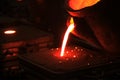 The metal workers is pouring molten metal to molds. Sand casting allows for smaller batches than permanent mold casting. Royalty Free Stock Photo