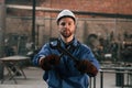 Metal wrenches in hands. Factory worker in blue uniform is indoors