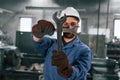 Metal wrenches in hands. Factory worker in blue uniform is indoors
