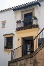 Metal wrought-iron balcony with flowers, windows and an icon on the white wall. Traditional spanish house in the city of Ronda, Royalty Free Stock Photo