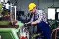 Metal worker turner operating lathe machine at industrial manufacturing factory.