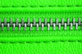 Metal zipper on intense green leather jacket or purse detail close up macro. The zipper is tightly closed binding