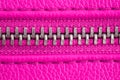 Metal zipper on intense pink purple leather jacket or purse detail close up macro. The zipper is tightly closed.