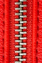 Metal zipper on intense red leather jacket or purse detail close up macro. The zipper is tightly closed. Royalty Free Stock Photo