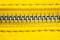 Metal zipper on intense yellow leather jacket or purse detail close up macro. The zipper is tightly closed