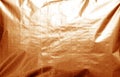 Metalized plasrtic wrap texture with crumples in orange tone Royalty Free Stock Photo