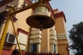 A metallic bell before a Hindu temple close up view hanging from a iron rod.
