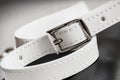 Metallic buckle on a white leather strap, selective focus. Modern womens accessorys