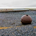 Metallic buoy on a shingle beach