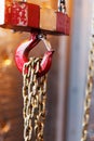 Metallic chain handle with red hook in technical room. Crane cargo hook